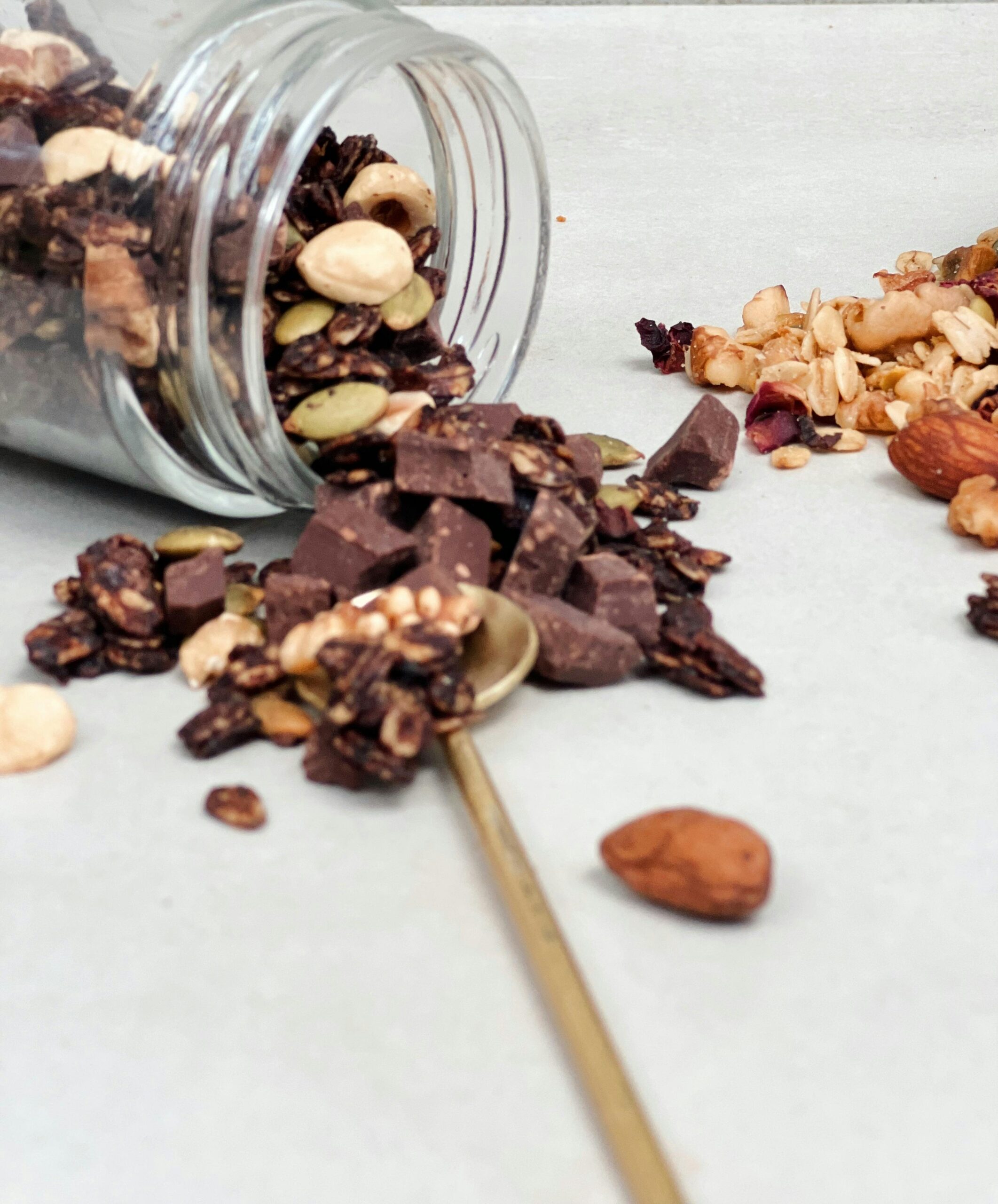 An open jar containing chocolate chips, nuts and cereal
