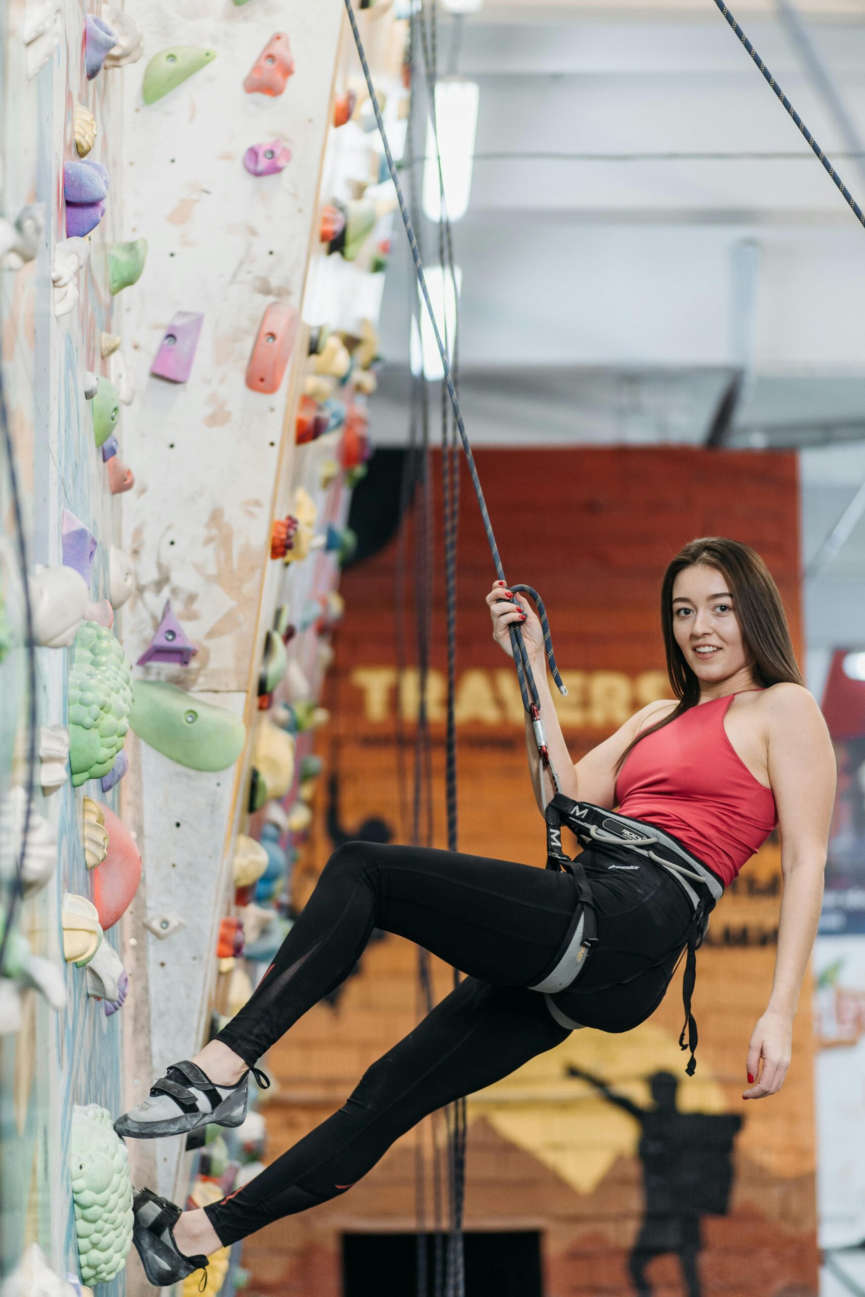 A young white, smiling, climbing in gym climbing shoes