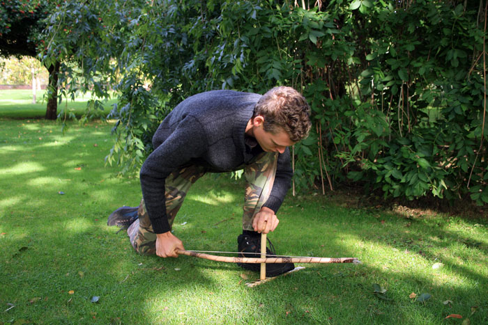 A man using a bow and drill method to light a fire as one of the techniques in  how to start a fire without matches or lighters